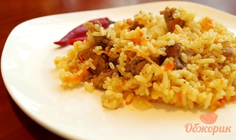 Oven-baked plov with beef and carrot, the rice grains separate and golden