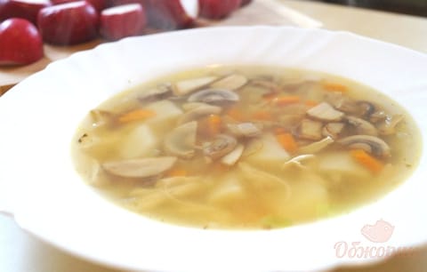 A bowl of clear chicken and mushroom soup with potato and browned mushrooms